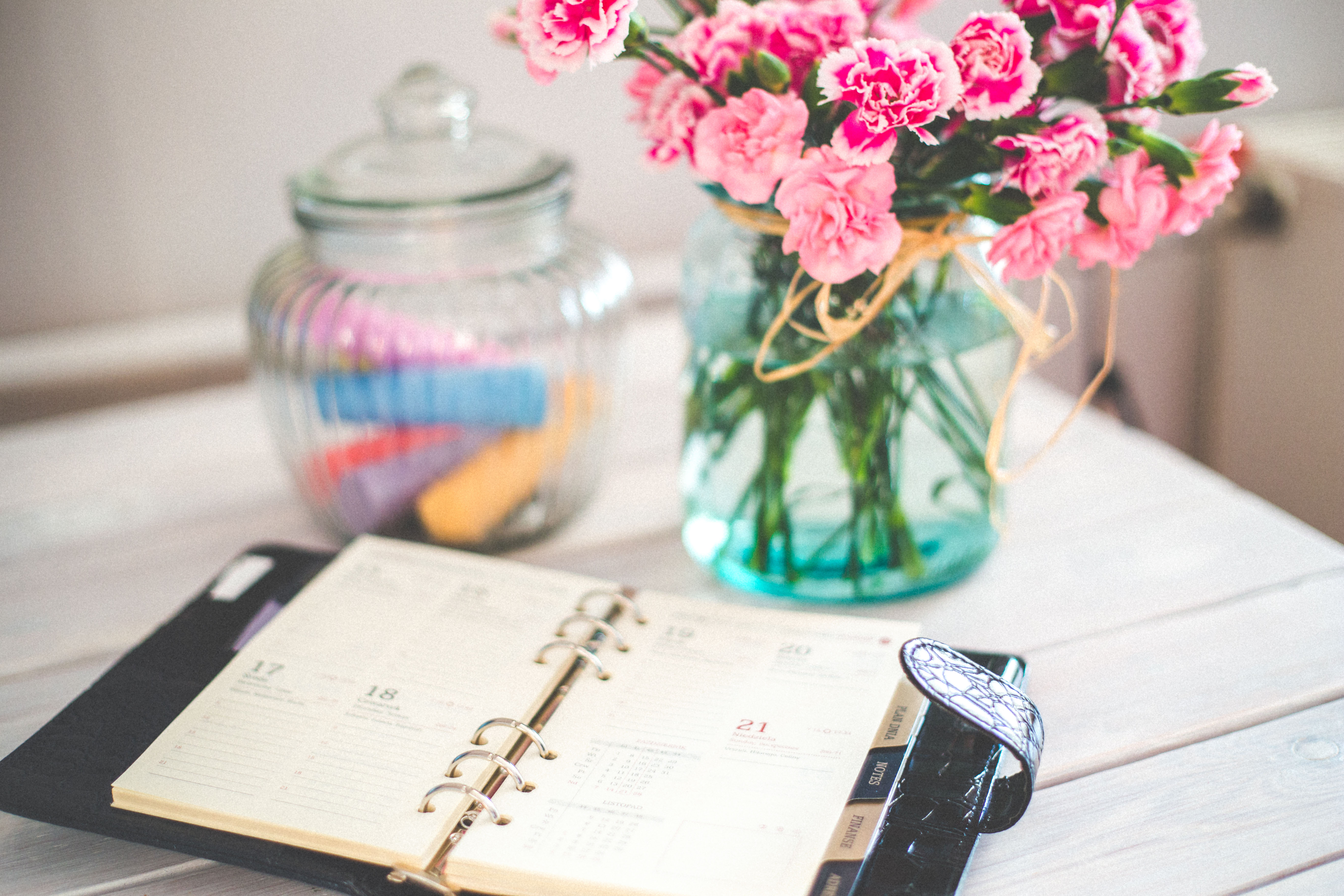 an organizer rests on a table next to a glass jar and flowers