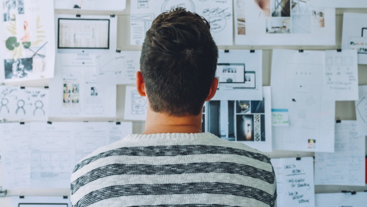 man looking at drawings on a board